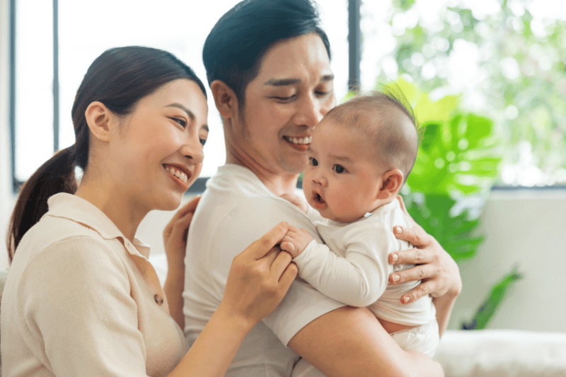 Smiling mother and father holding newborn son at home