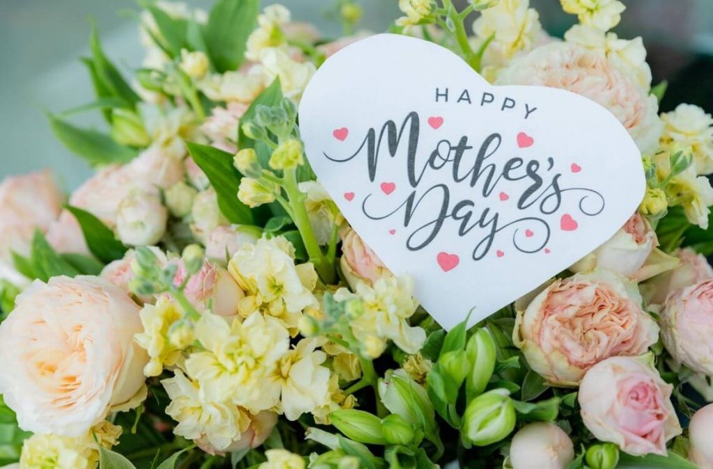 beautiful floral bouquet with a happy mother's day card , featuring pastel roses, lisianthus, and greenery.pale pink roses.pink blossom flower bouquet