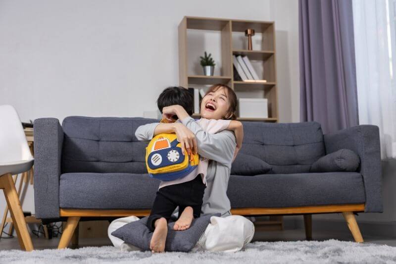mother happily hugging her son with school backpack at home, showing family love, warmth, and joyful reunion after school day