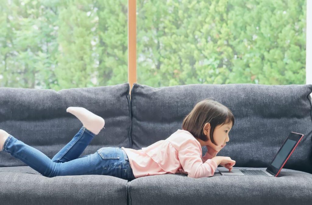 girl lying on sofa facing laptop screen