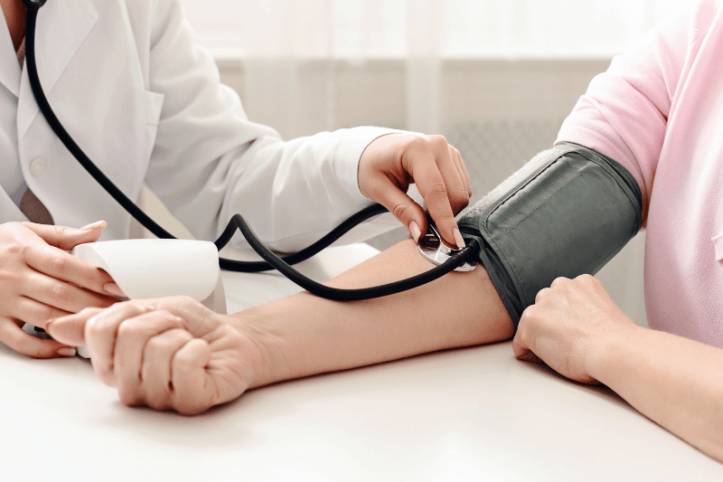 A doctor in a white coat is carefully examining a patients arm while drawing blood for a medical test.