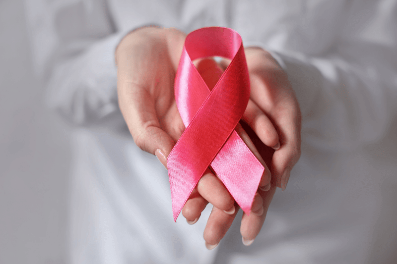 Pink ribbon in woman hands for breast cancer awareness, symbolic bow color raising awareness on people living with women's breast tumor illness