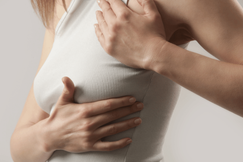 Woman doing a self-breast examination, studio shot