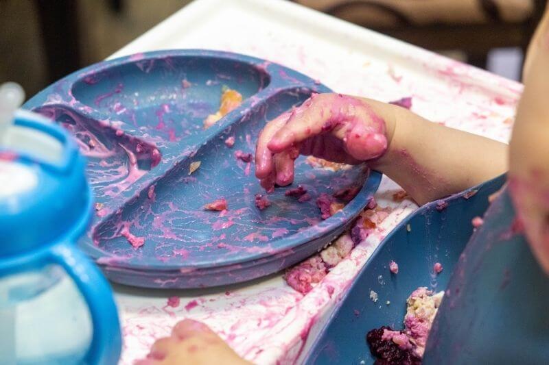 Baby Enjoying a Messy Meal in High Chair