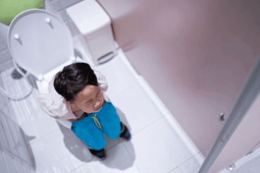 Asian boy sitting constipated on toilet