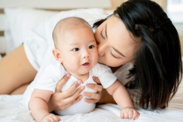 Portrait Mother is taking care of newborn baby wearing clean white clothes In the bedroom