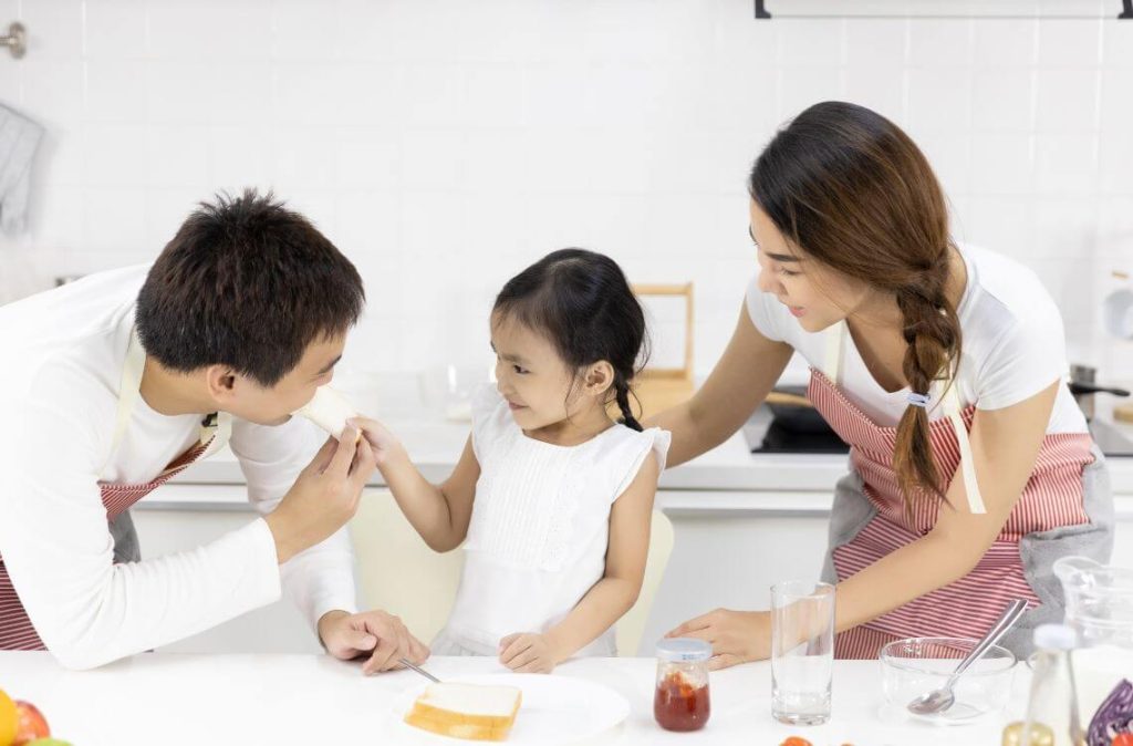 Mother and Daughter are eating breakfast in the kitchen at home. Bread with jam. Healthy food concept