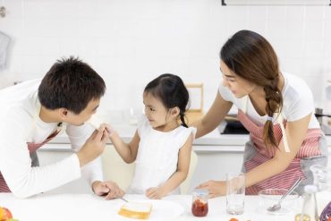 Mother and Daughter are eating breakfast in the kitchen at home. Bread with jam. Healthy food concept