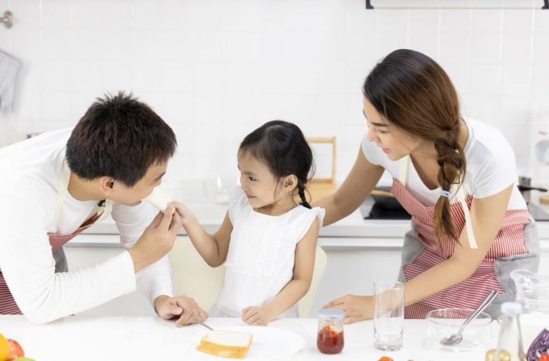 Mother and Daughter are eating breakfast in the kitchen at home. Bread with jam. Healthy food concept