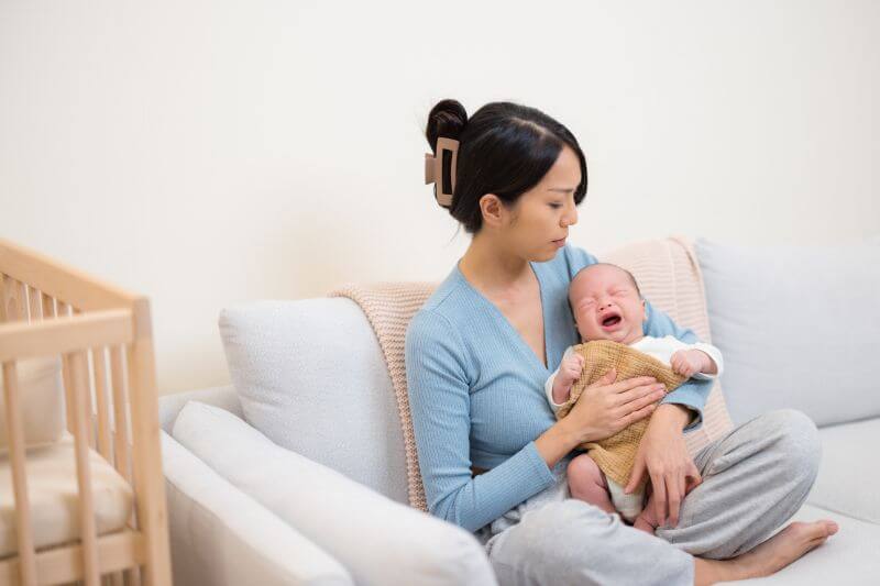 Mother comforting crying newborn baby at home