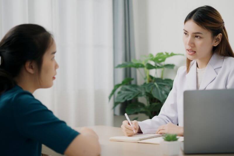 woman seeing doctor at medical clinic checking on symptoms
