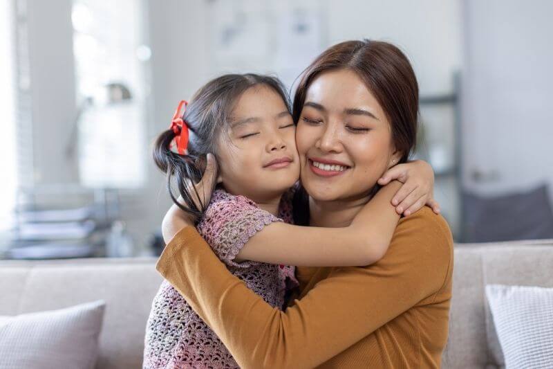 cheerful asian toddler daughter hugging happy mother Good time at home.