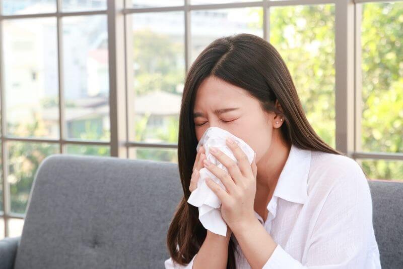 beautiful asian woman sick with the flu have a stuffy nose Hold a tissue to cover your mouth. Prevent the virus from spreading. health care concept