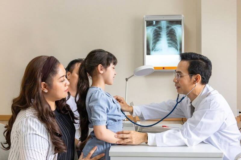 Asian doctor is diagnosis young girl using stethoscope for lung checkup and side effect on coronavirus with parent and family in her appointment in hospital