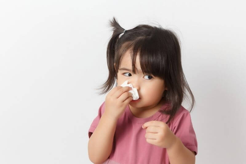 Little asian girl holding a tissue and blow her nose. Kid with cold rhinitis. virus and infection. Coronavirus symptom