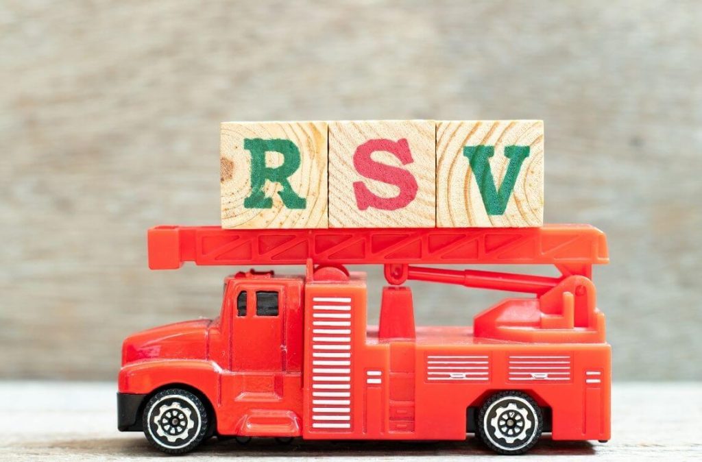 Fire ladder truck hold letter block in word RSV (Abbreviation of Respiratory syncytial virus) on wood background