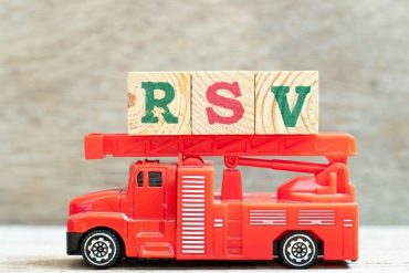Fire ladder truck hold letter block in word RSV (Abbreviation of Respiratory syncytial virus) on wood background
