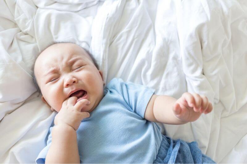 cute baby cry on white bedspread