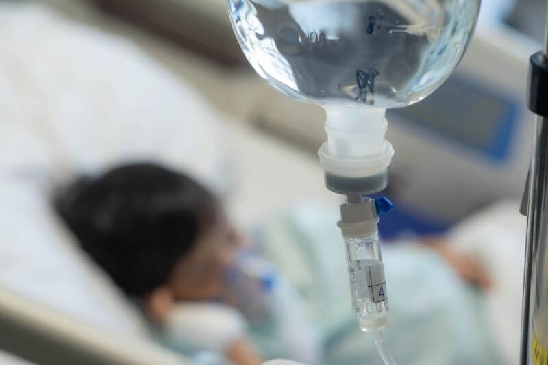 an Asian todler in hospital with intravenous saline. Sick children, infected with the virus, are lying and being treated in beds in hospitals.