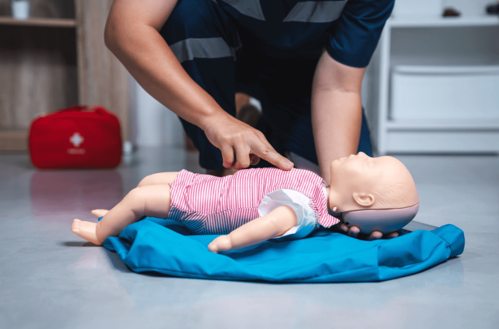 Adult demonstrating CPR on an infant manikin during training.