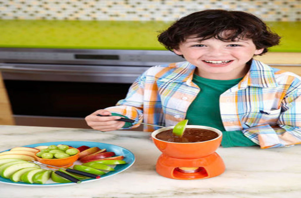 a boy dipping an apple into a caramel fondue