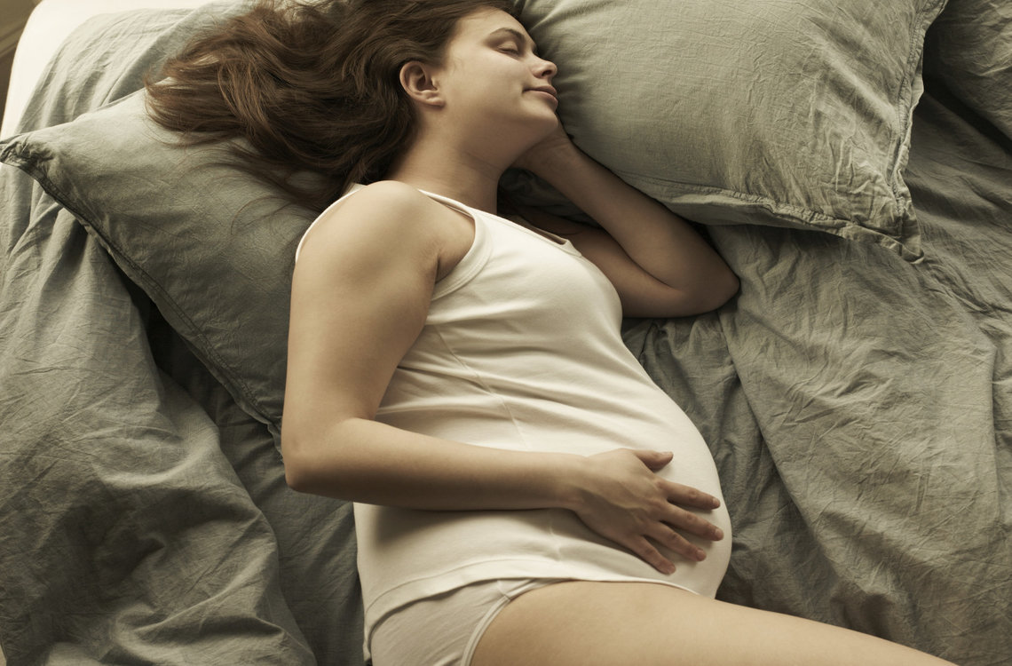 Pregnant woman sleeping on bed, high angle view