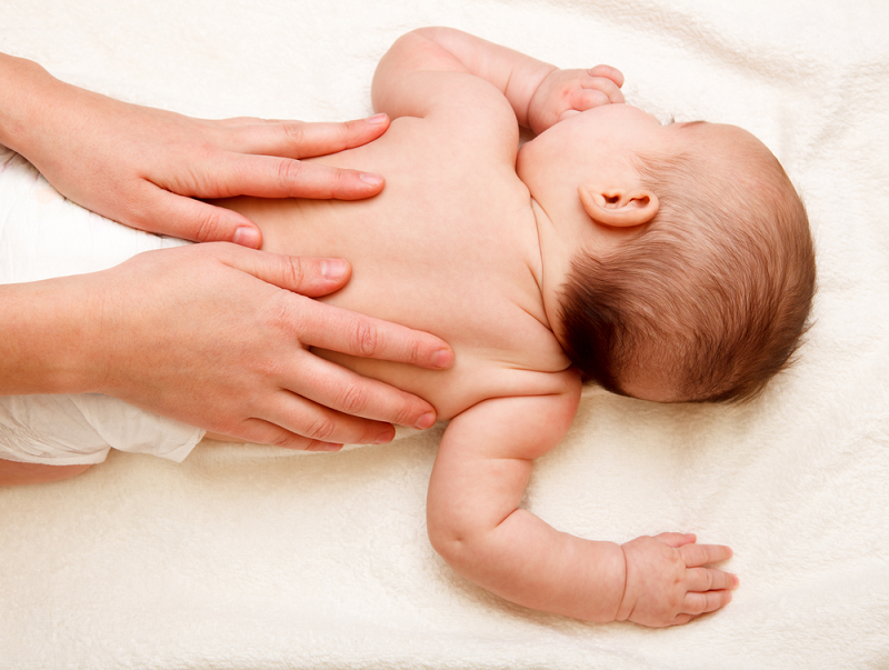 dua tangan sedang urutkan badan bayi