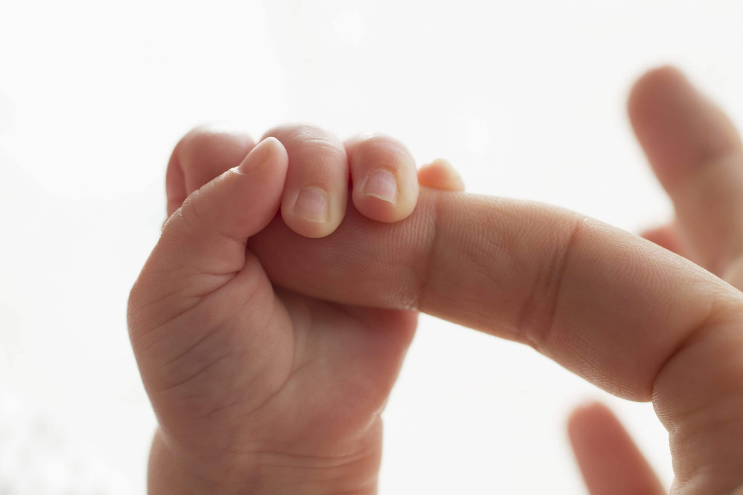 bayi menggenggam jari ibu