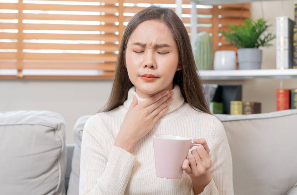 wanita mencuba cara hilangkan sakit tekak sambil memegang cawan